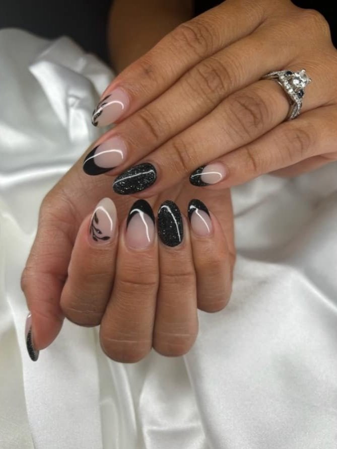 Close-up of hands with black and white decorated nails, one hand resting on top of the other, with a wedding ring visible on the ring finger of the top hand.