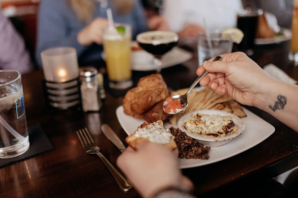 spooning tomatoes on pita with feta dip