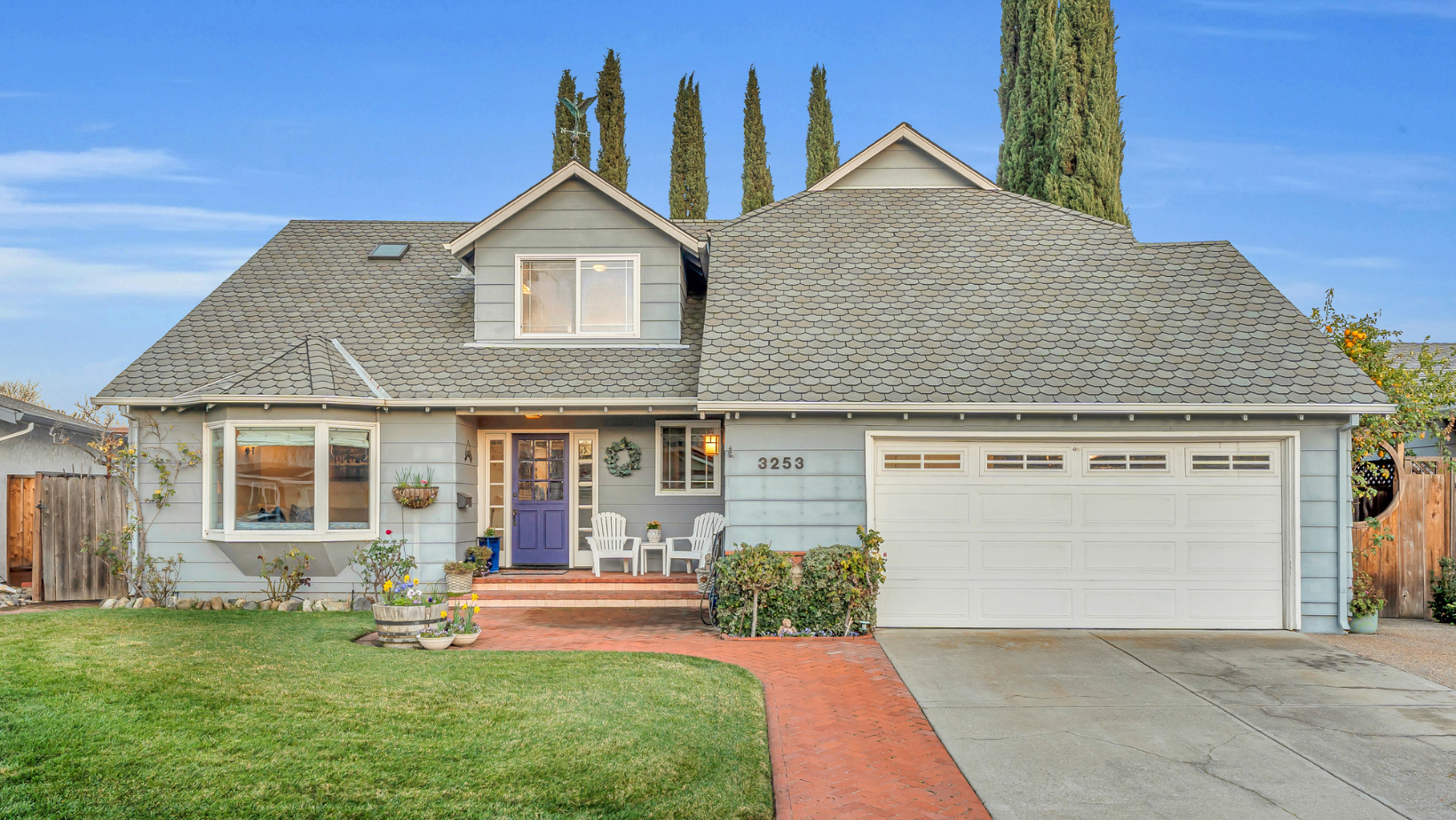 blue single family home on Flemington court in Pleasanton, California with large grass front yard and lots of plants on the patio with a blue door