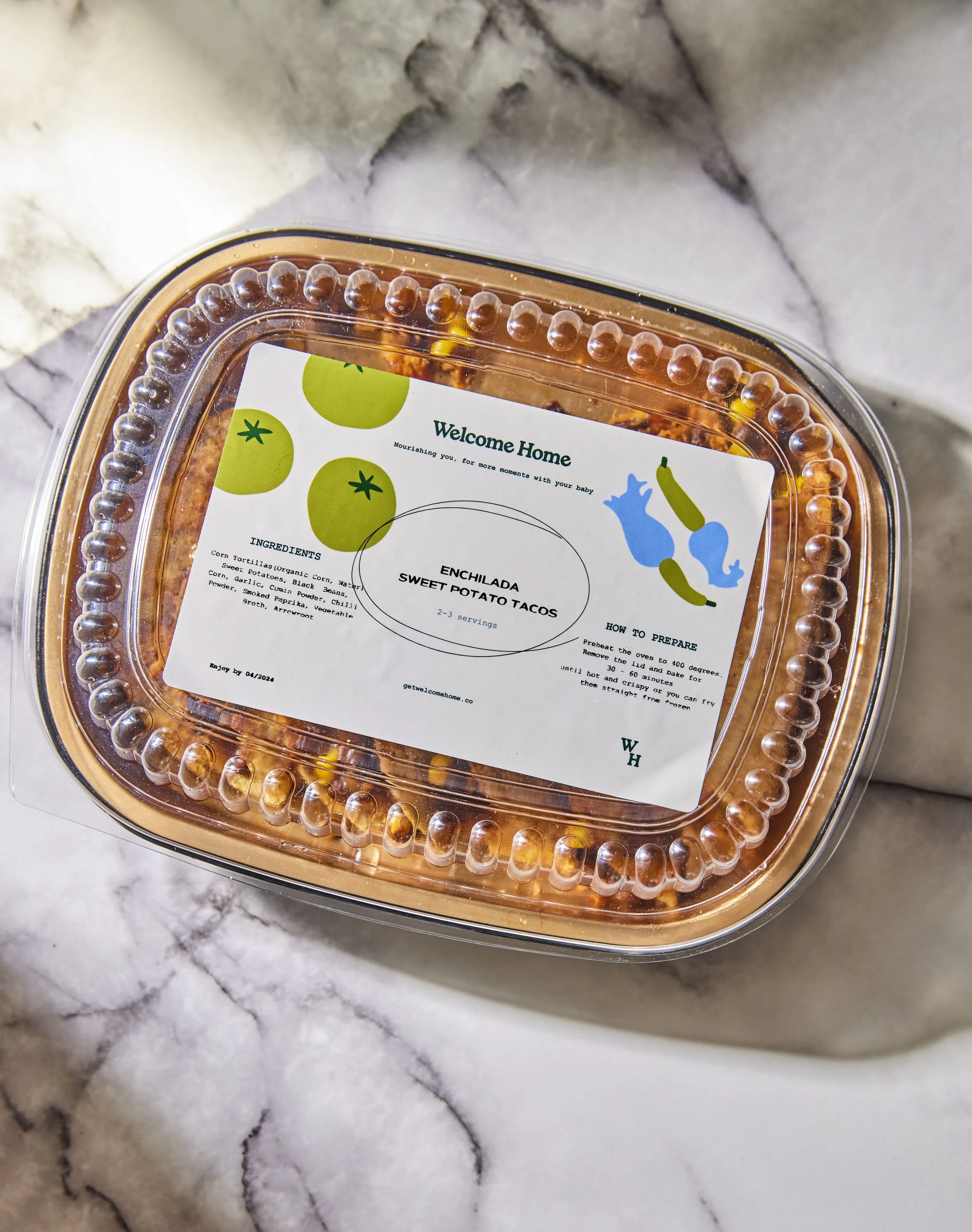 Plastic container of enchilada sweet potato tacos with a white label featuring green tomatoes, blue and green illustrations of a pig and cucumber, and cooking instructions.