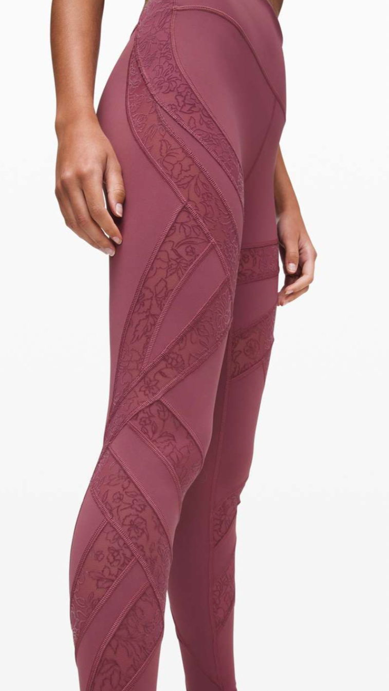 Close-up of a woman's lower body wearing maroon athletic leggings with floral and zigzag detailing.
