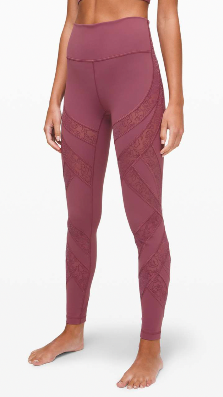 Close-up of a woman's lower body wearing mauve athletic leggings with a floral pattern on the sides, standing barefoot against a white background.
