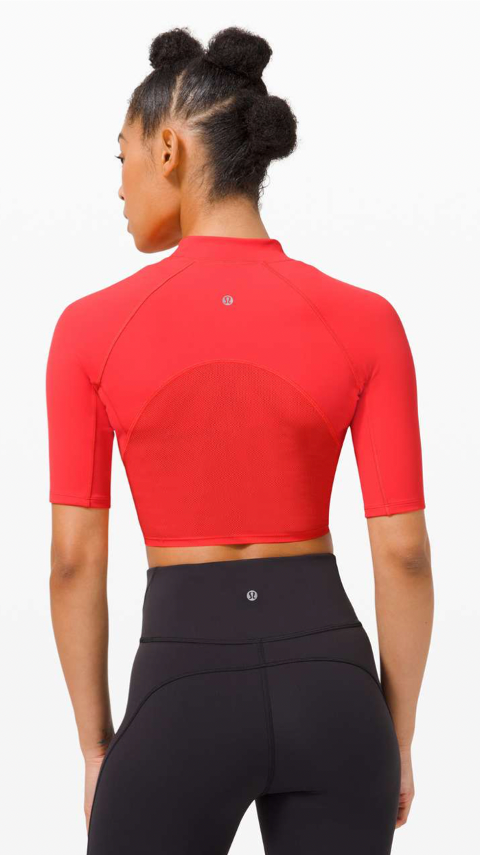 Back view of a woman in red athletic cropped top and black high-waisted leggings.