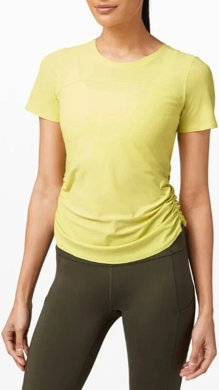 A woman wearing a yellow athletic T-shirt and dark green leggings.