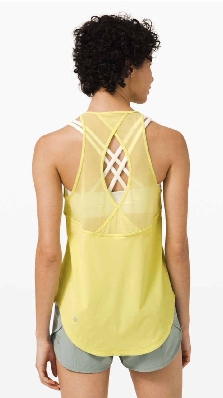 Woman wearing a yellow running vest with a crisscross back design, standing with her back to the camera.