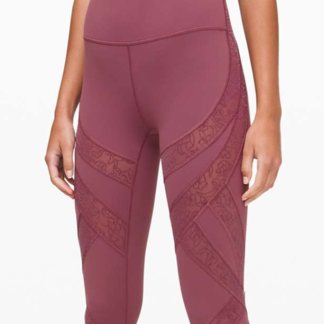 Close-up of a woman wearing maroon athletic leggings with floral and geometric sheer panels.