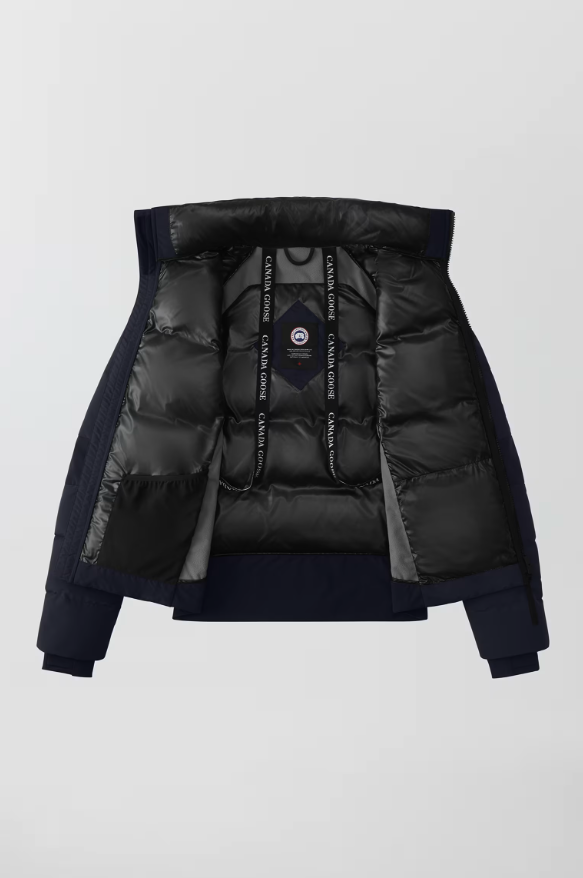 The image shows the inside of a navy blue winter jacket with a shiny black insulated lining and a hood. The lining has drawstrings with 'CANADA GOOSE' written on them.