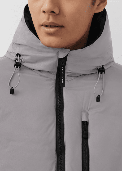 Close-up of a man wearing a light gray, waterproof jacket with a high collar and adjustable hood.