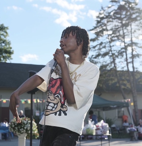 Medium shot of Darius holding a microphone and performing to an unseen crowd