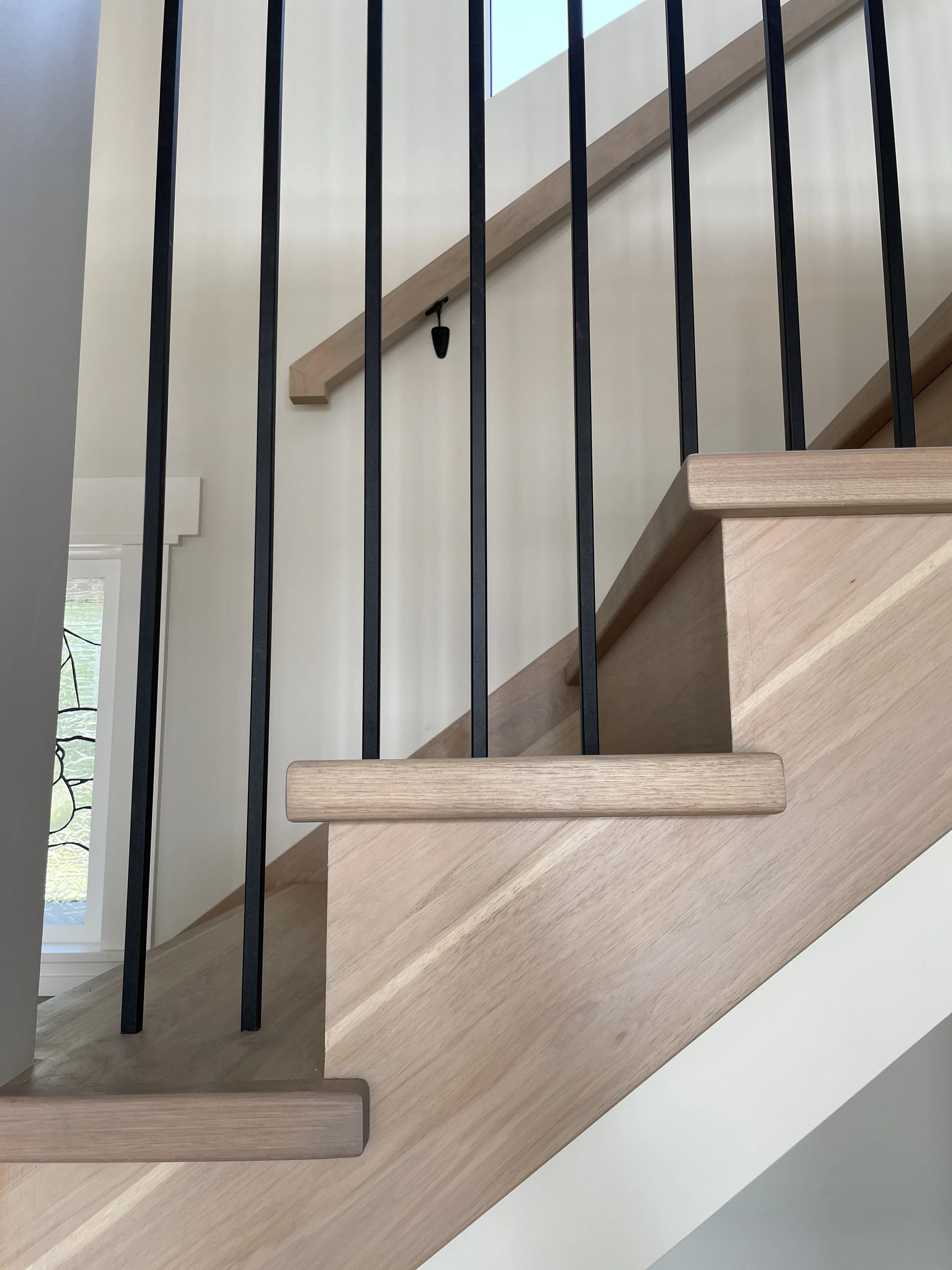 Close-up of a staircase with wooden steps and black metal balusters, viewed from below.