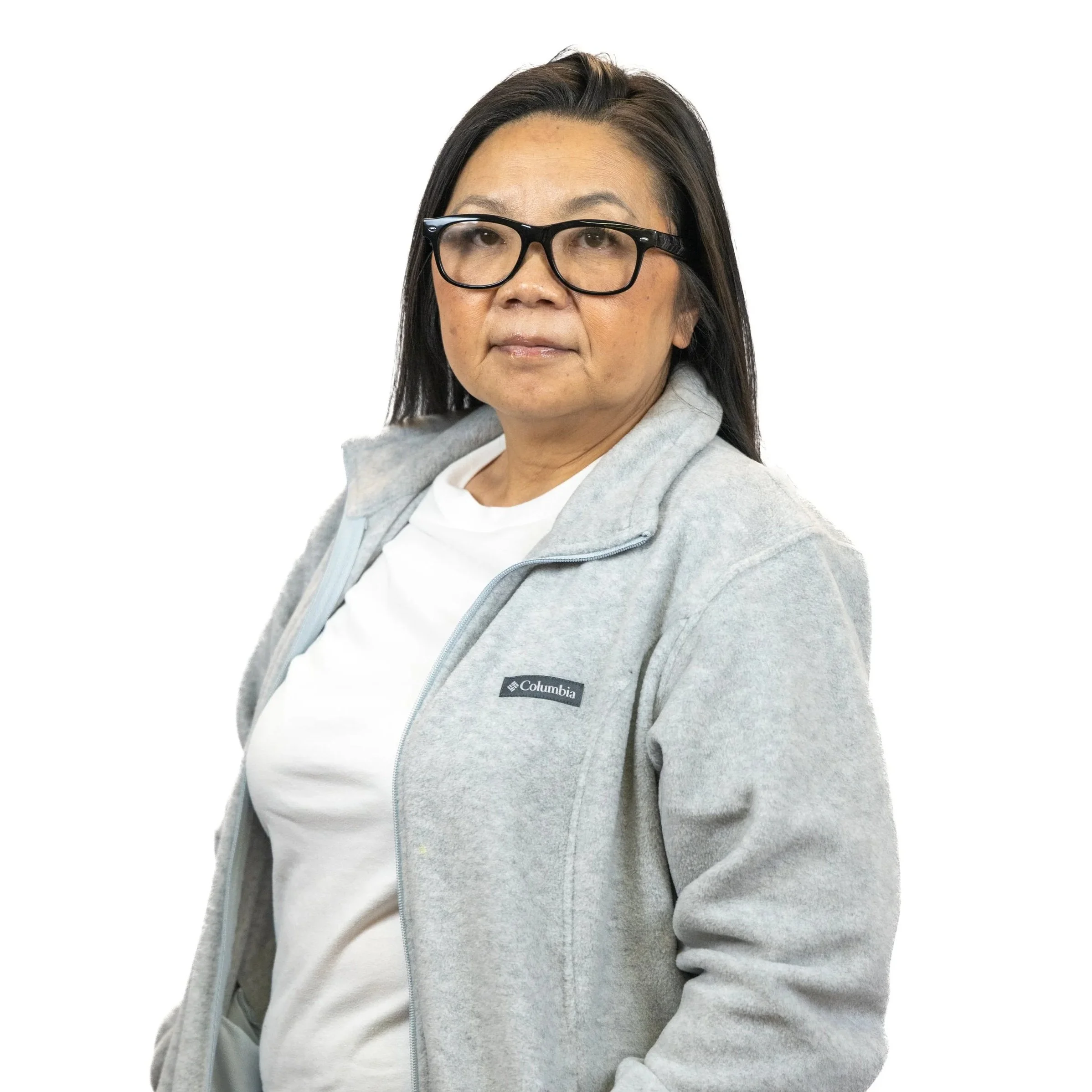 Woman with glasses wearing a gray Columbia jacket and white t-shirt, standing against a white background.