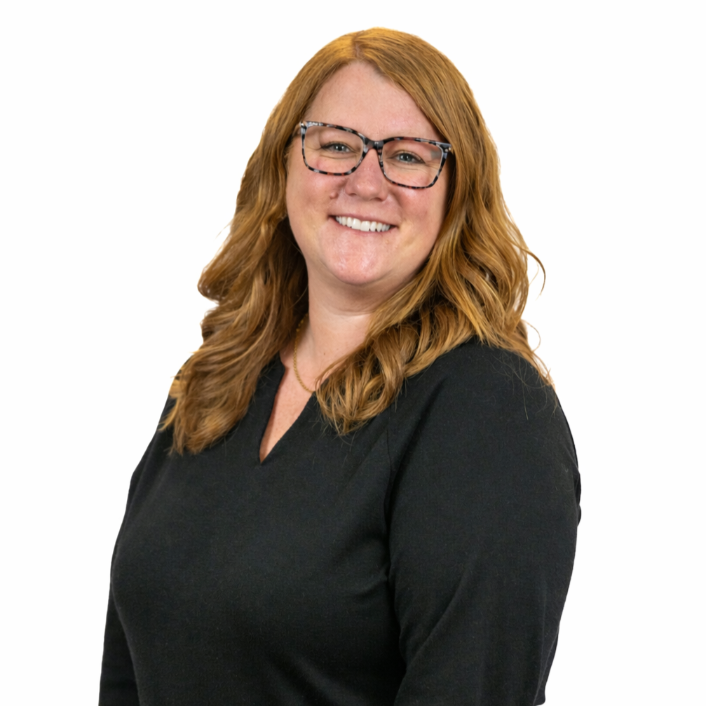 Woman with red hair, glasses, wearing a black top, smiling, white background.
