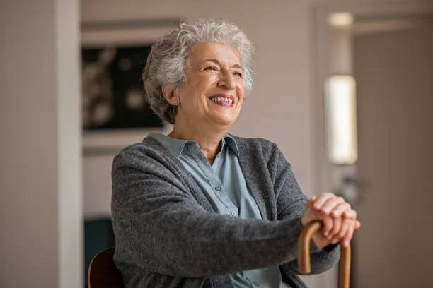 Older adult female holding a cane while smiling 