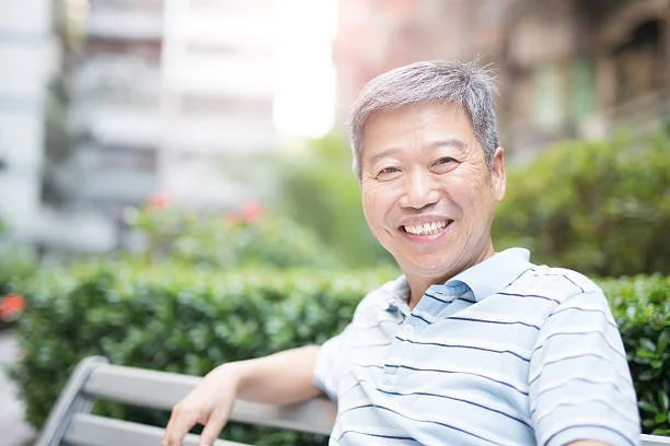 Asian American man smiling while sitting on a bench