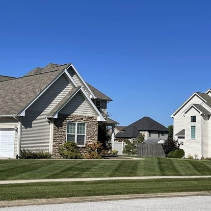 Suburban houses with well-maintained lawns and clear blue sky
