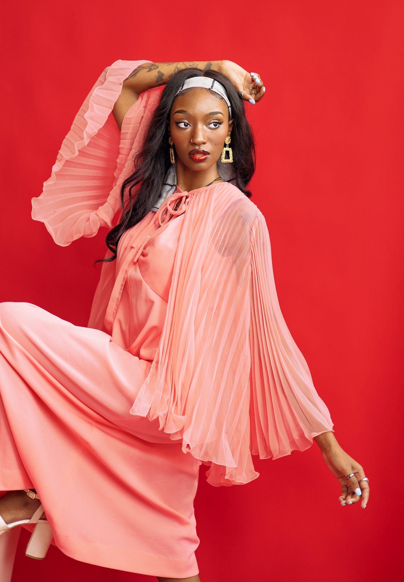 A woman dressed in a flowing pink pleated dress for a creative editorial shoot in Cincinnati