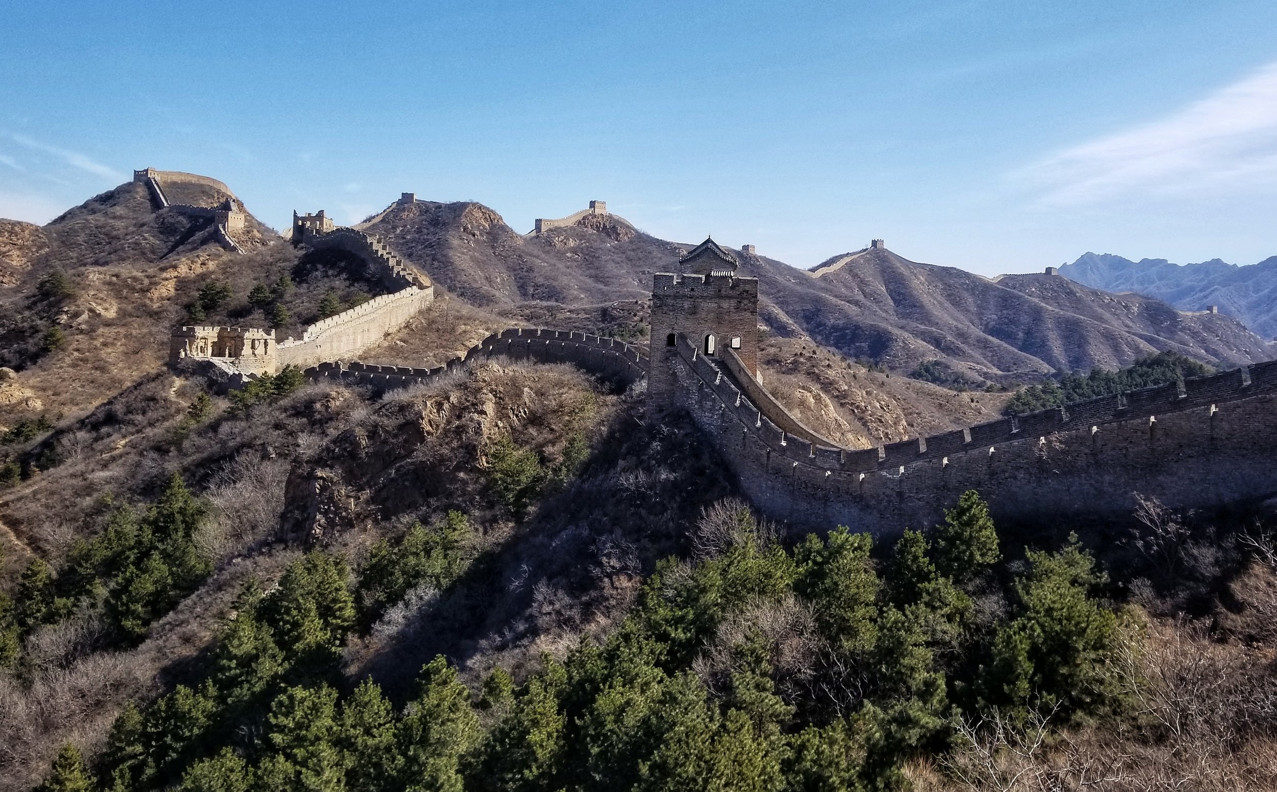 A section of the Great Wall of China stretching over the mountains under a clear blue sky.
