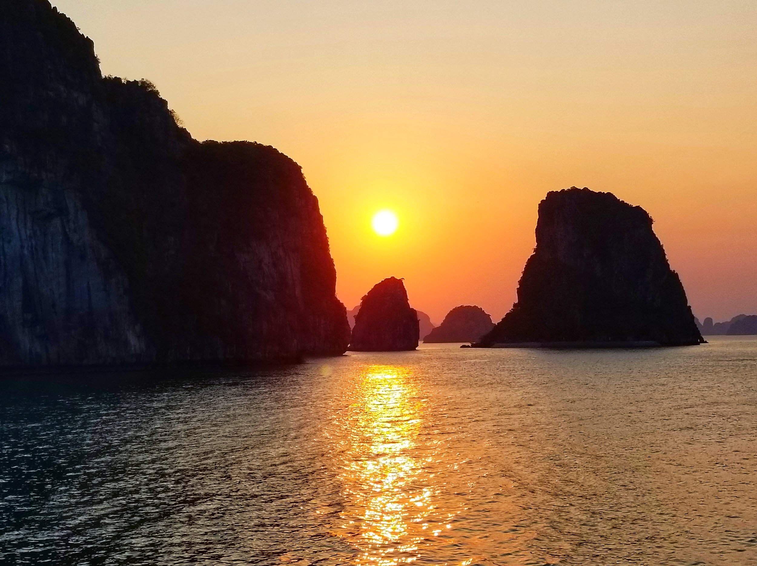 Sunset over water with limestone islands in the background.