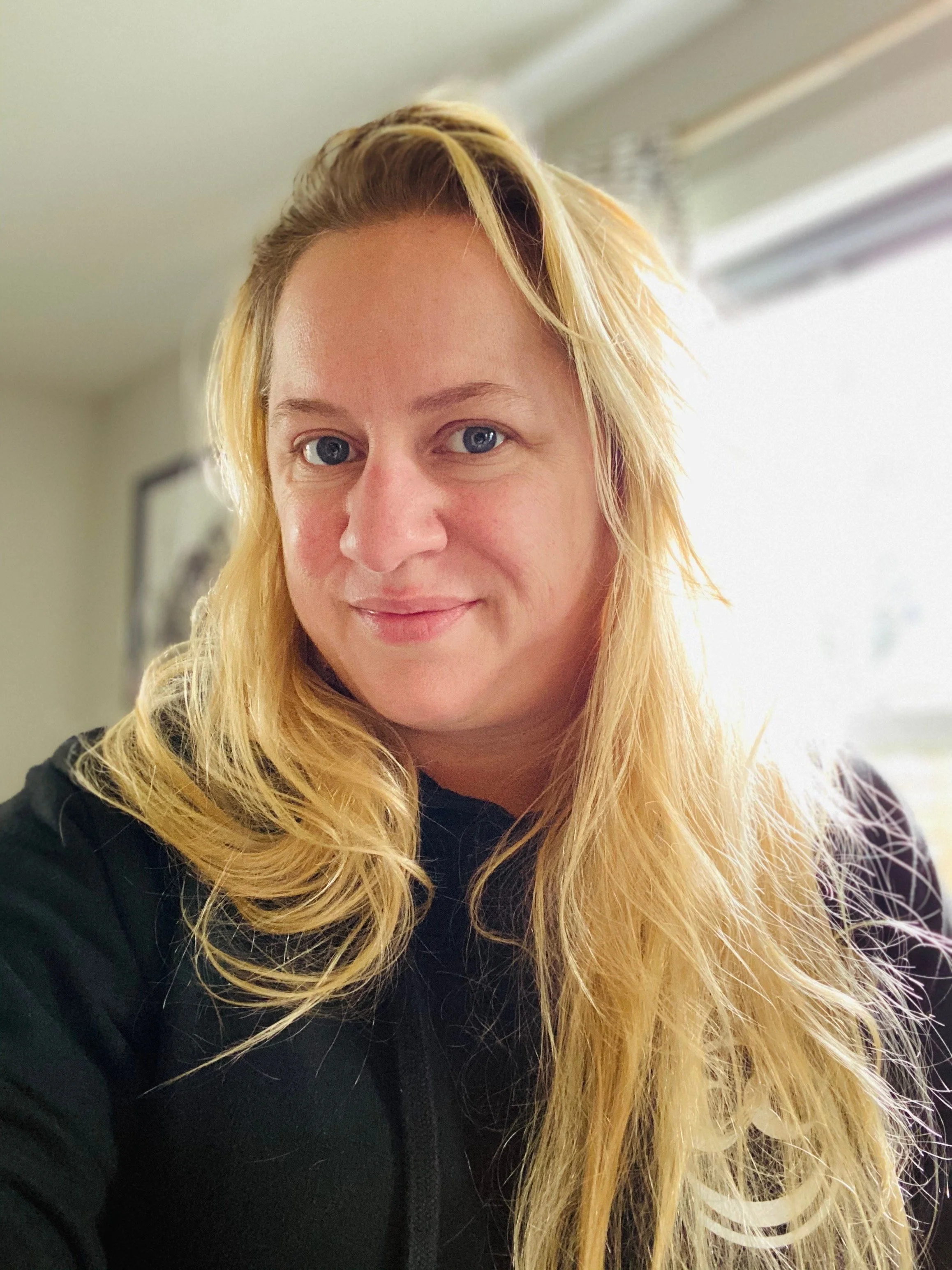 Shannon Dooley, wearing black sweater, long golden blonde hair, blue eyes. Natural makeup.