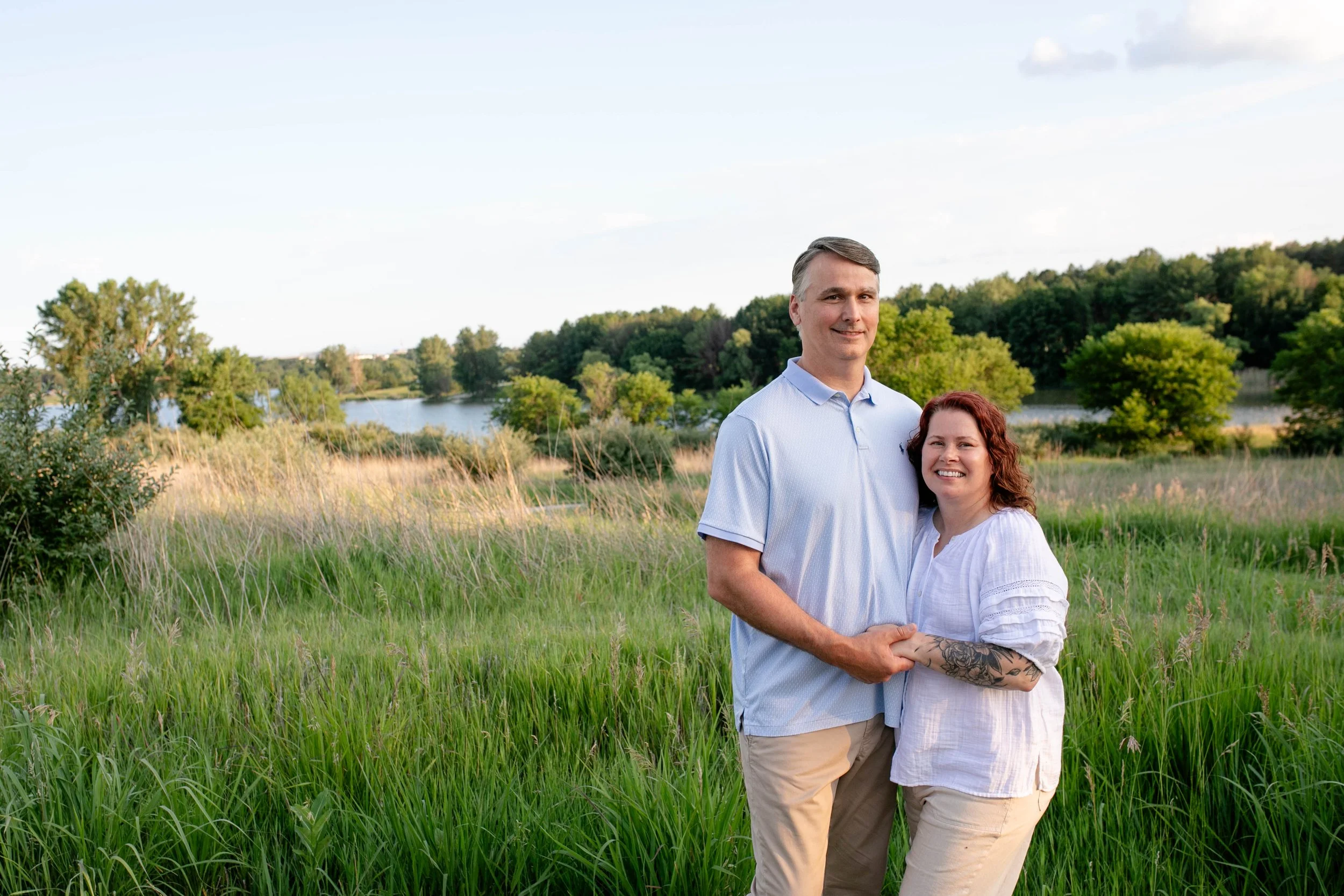 Man and woman standing next to each other and holding hands in front at park in Omaha Nebraska