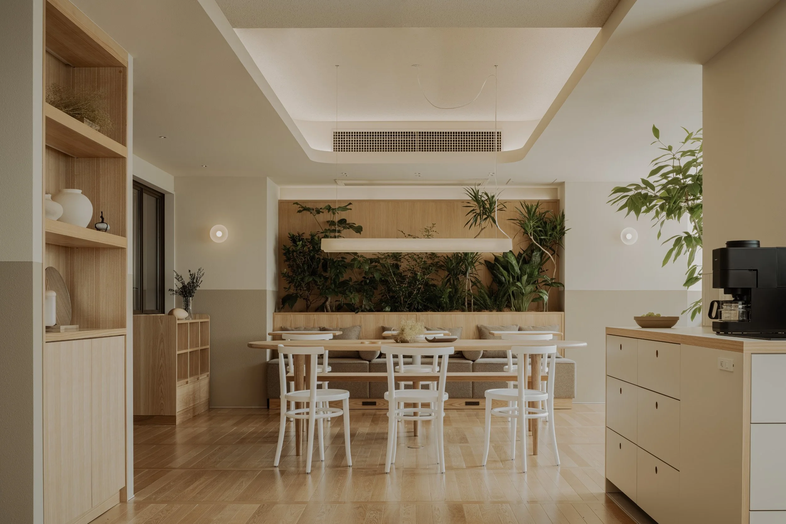 santasがPMを手掛ける「HAUN 蔵前」のダイニングエリア。壁面一面の木製パネルにグリーンを配し、ミニマルな飾り棚を設けることで、カフェのような洗練された寛ぎを演出。入居者が心地よく集える、自然素材を活かしたインテリアデザイン