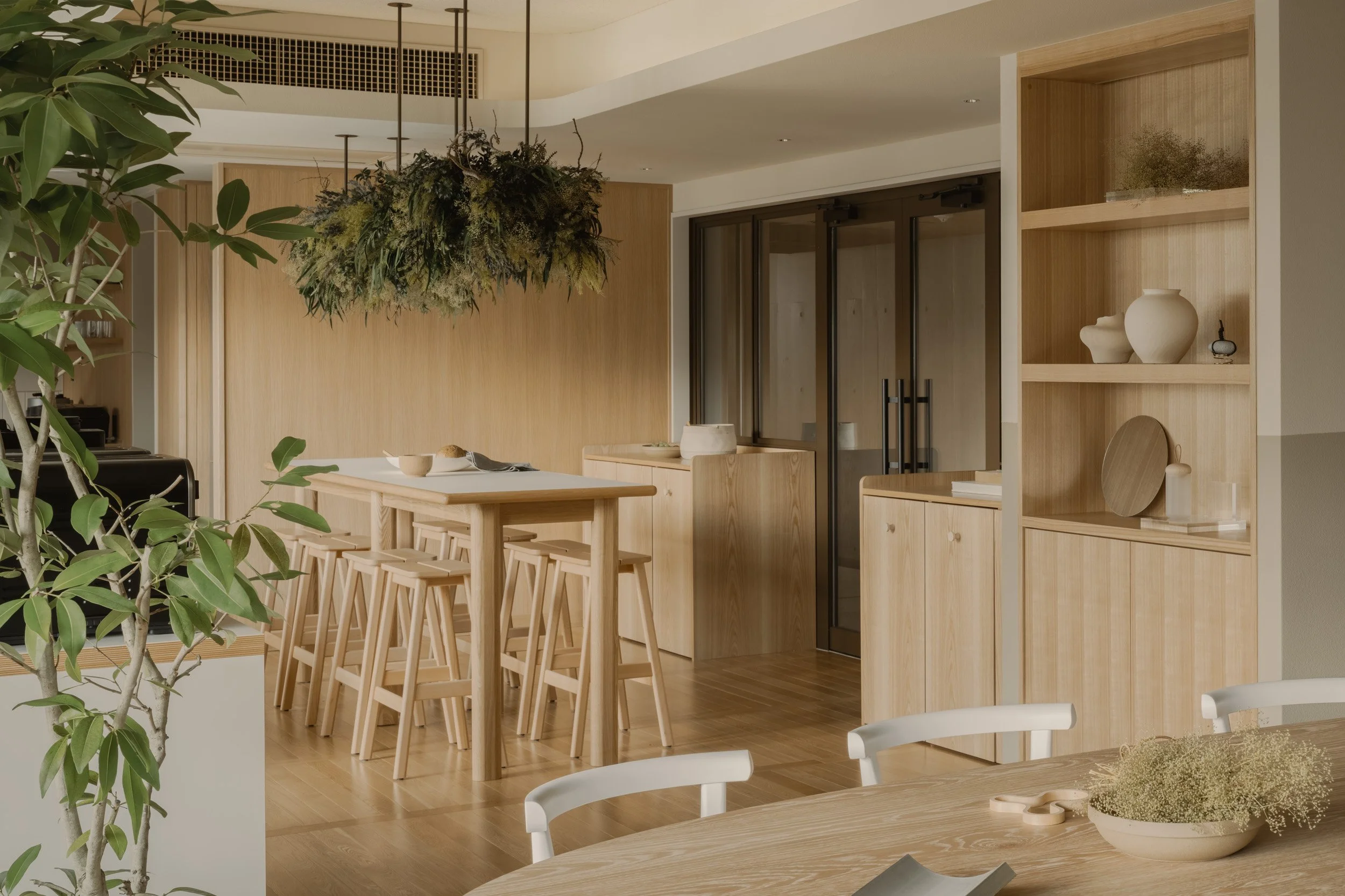 santasがPMを担当した「HAUN 蔵前」のシェアキッチン。入居者のコミュニケーションの起点となるアイランドキッチンを配し、蔵前の街らしいクラフト感漂う陶磁器のディスプレイやバイオフィリックな吊り植物で彩られた、温かみのあるミニマルデザイン