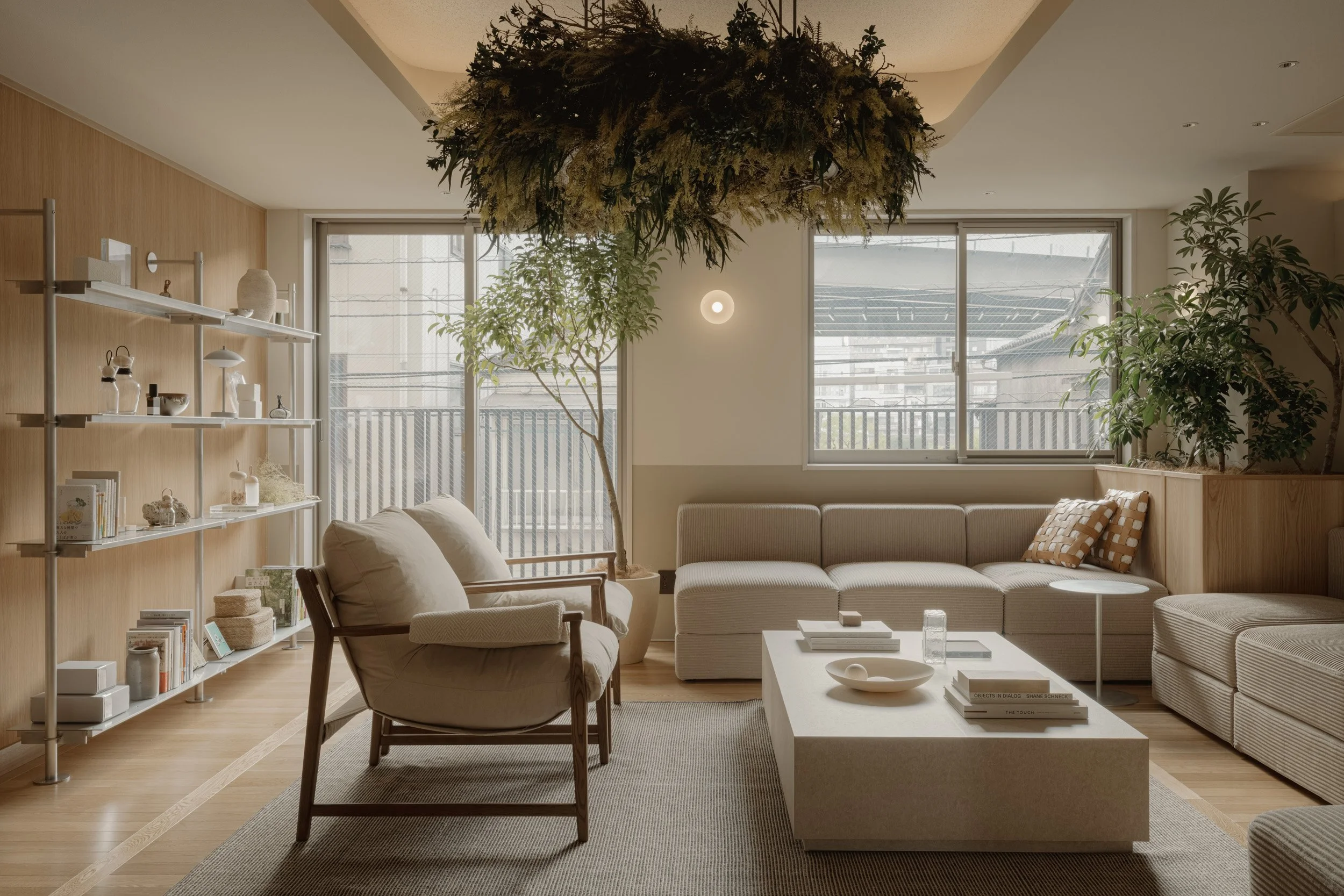 santasがPMを担当した「HAUN 蔵前」のリビングエリア。ニュートラルなベージュのインテリアに大きな窓と豊かな緑を組み合わせ、開放感と安らぎを演出。棚に並ぶ小物のスタイリングまでこだわり、蔵前らしい洗練されたライフスタイルを表現した空間設計