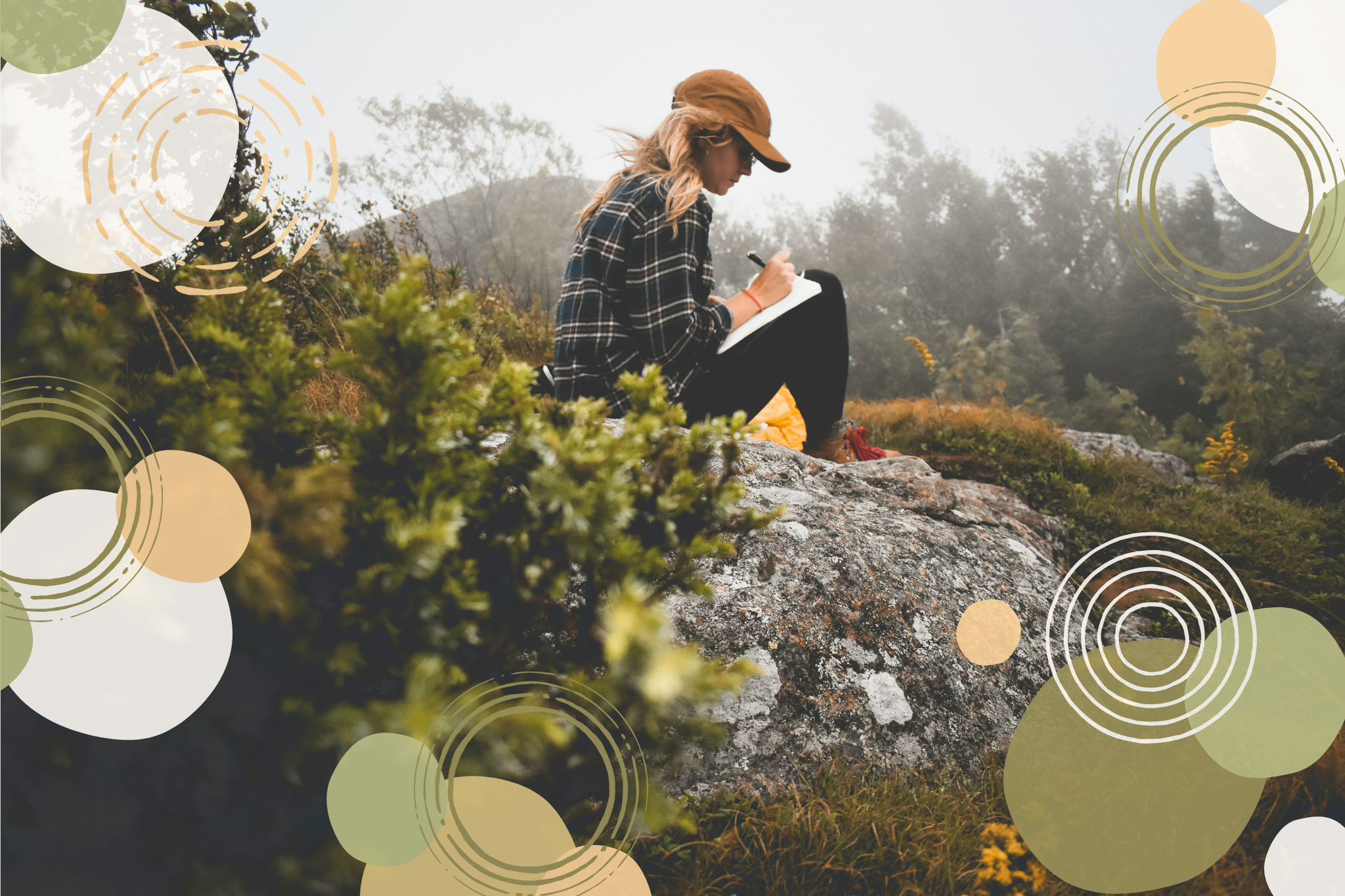 Woman with long blond hair wearing a brown hat a plaid shirt and black pants, sitting on a large rock in a foggy outdoor environment, writing in a notebook.