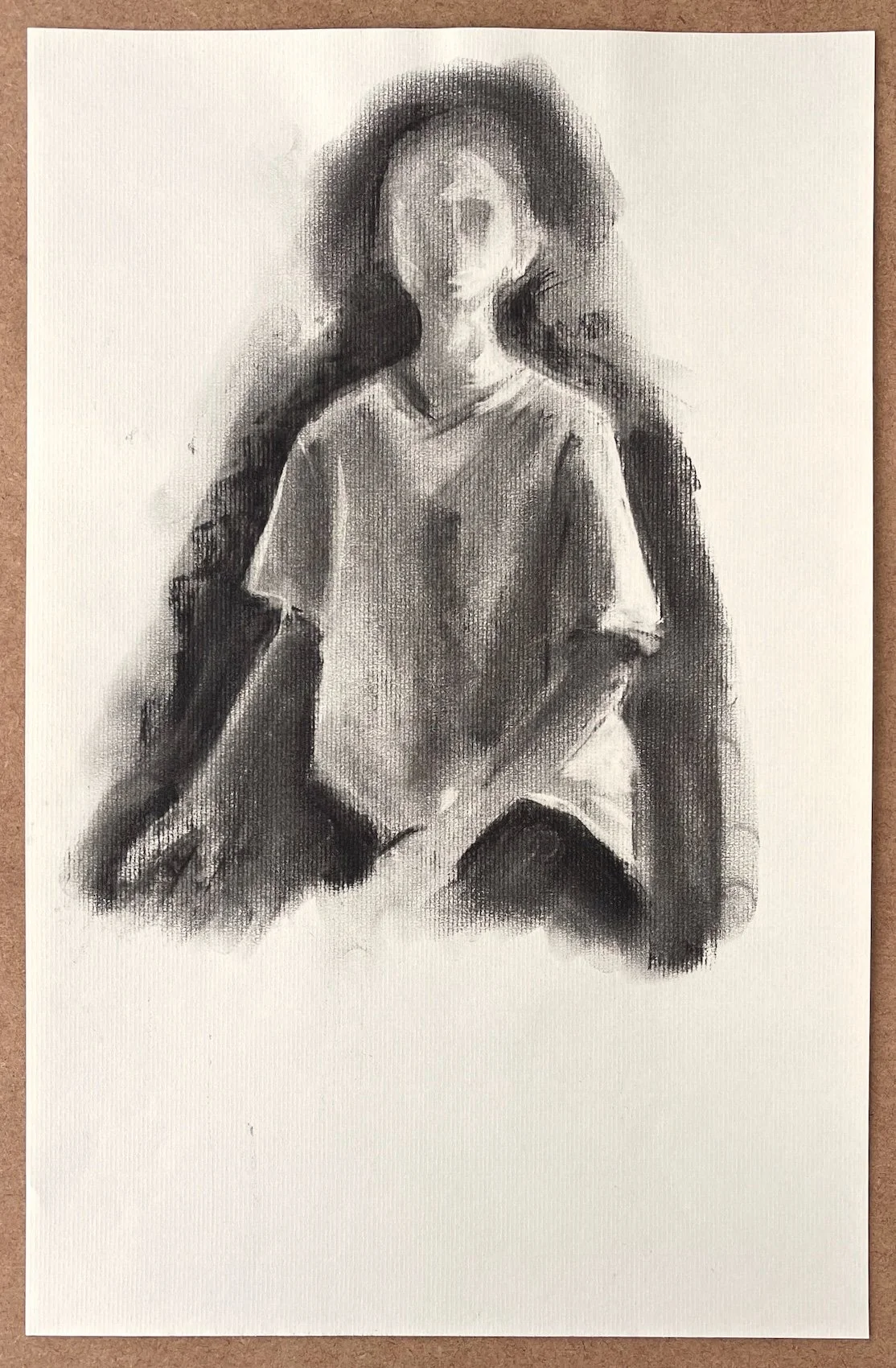 Full sheet view of Suspended, original charcoal drawing showing a partially resolved seated figure surrounded by soft charcoal shadows and a large area of untouched paper.