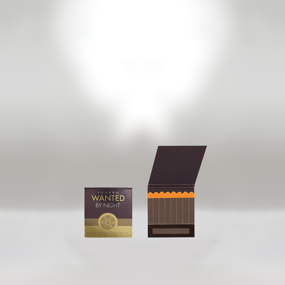 Box of Azzaro Wanted by Night perfume and an open black and orange matchstick box on a white background.