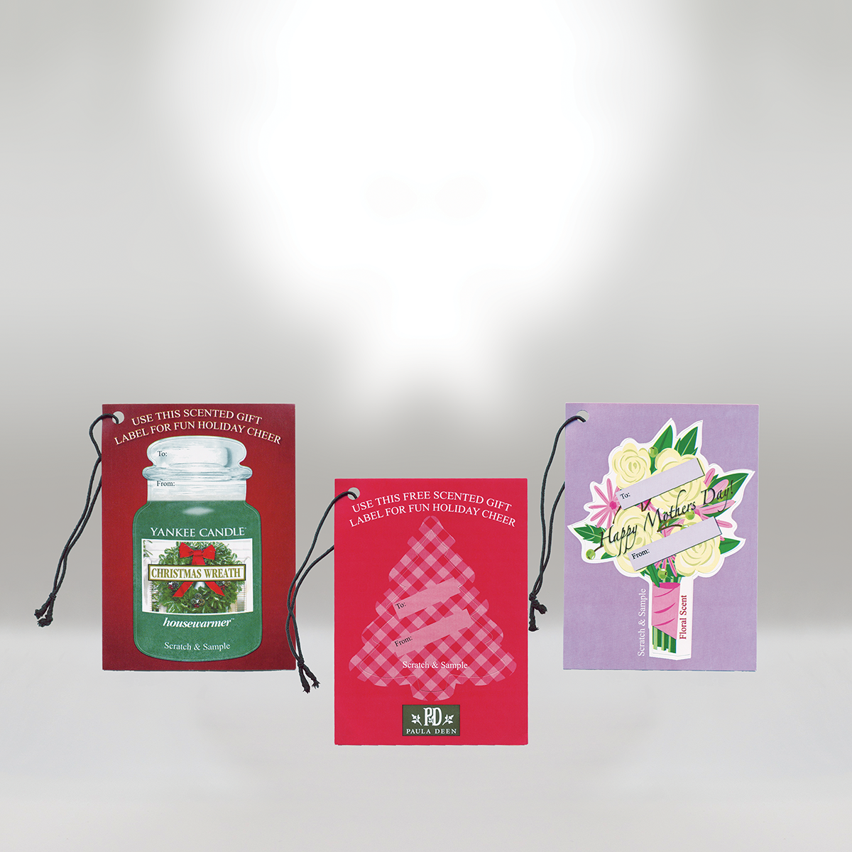 Three gift tags with holiday and Mother's Day themes, each with a string for attaching, displayed against a plain background. The left tag features a candle with a Christmas wreath, the middle tag has a red checkered Christmas tree, and the right tag shows a bouquet of flowers with a Mother's Day message.