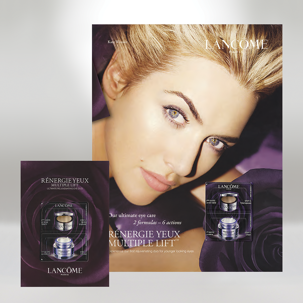 Lancôme skincare product display featuring a woman with blonde hair, blue eyes, and makeup, with two packages of Rénergie Yeux Multi-Action Lift eye cream in front of the display.