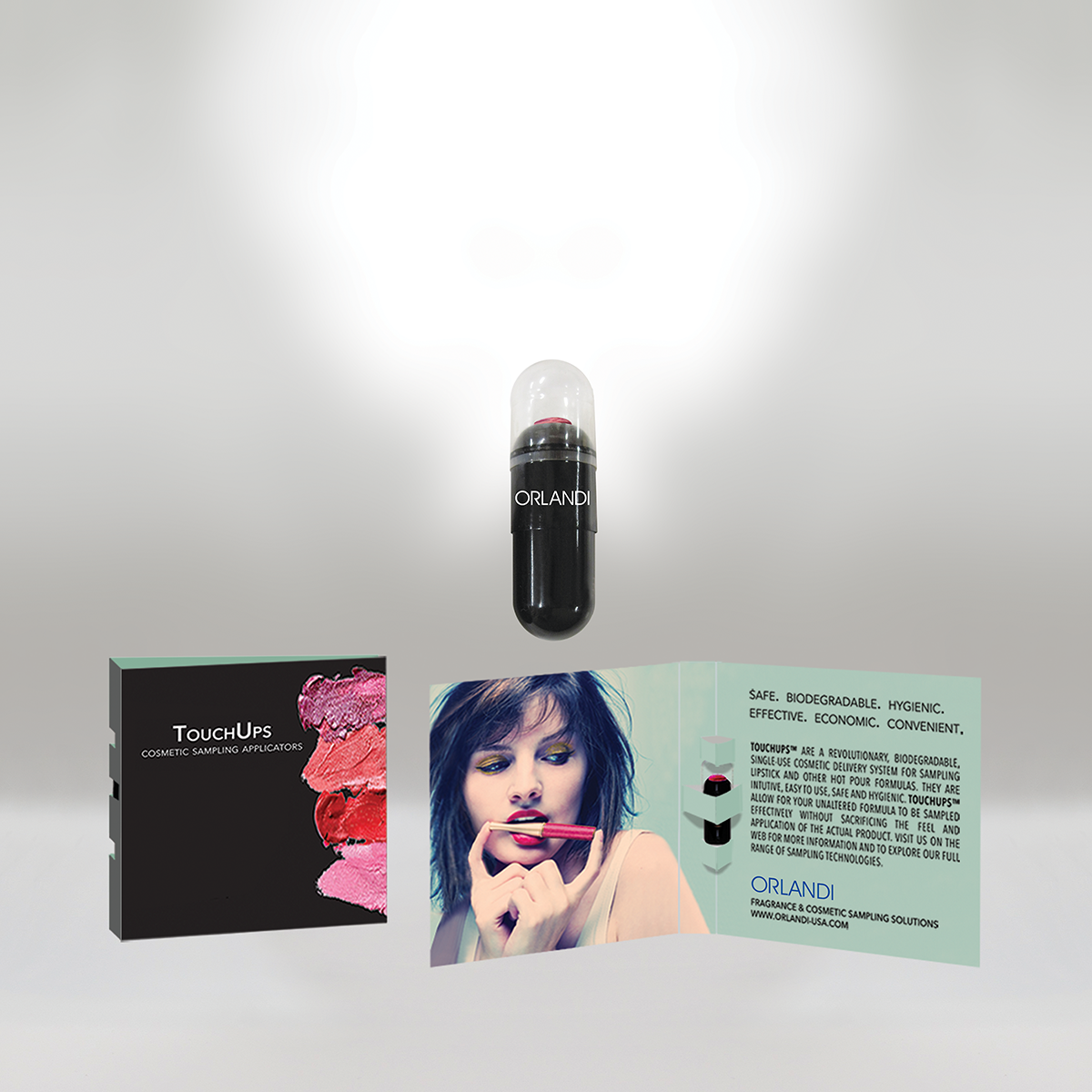 Cosmetic sampling applicator capsule with 'ORLANDI' branding, and a brochure showing a woman with vibrant makeup and a lip gloss, along with product information and packaging.