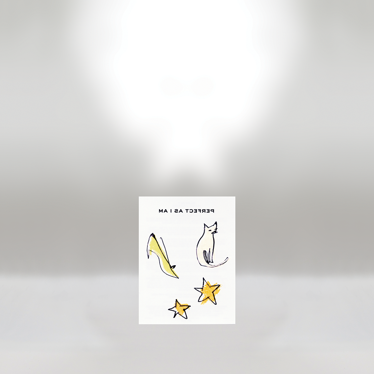 A sticker with a drawn banana, a sitting cat, and two stars. The text is upside down and reads 'PERFECT AS I AM'.