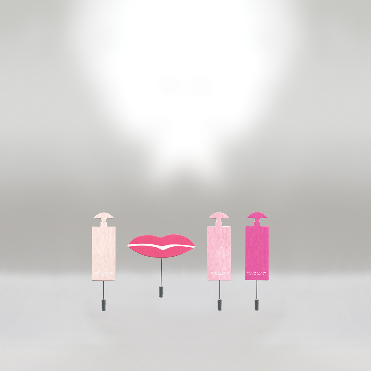 Four perfume bottles shaped like lips and perfume bottles with pink shades, set against a light gray background.