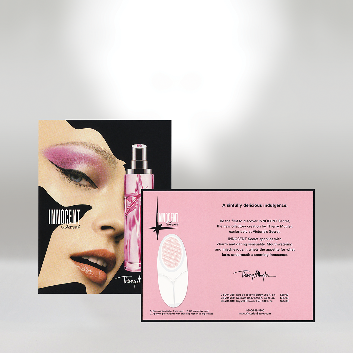 Victoria's Secret Innocent Secret perfume advertisement with a woman's face featuring pink eyeshadow, winged eyeliner, and neutral lipstick, along with promotional material about the perfume, a pink bottle, and product descriptions on a pink card.