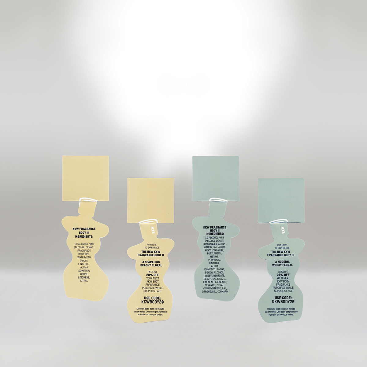 Four fragrance tags with blank note paper attached, each displaying different product details and promotional codes. The tags are shaped like bottles and arranged in a row against a plain background.