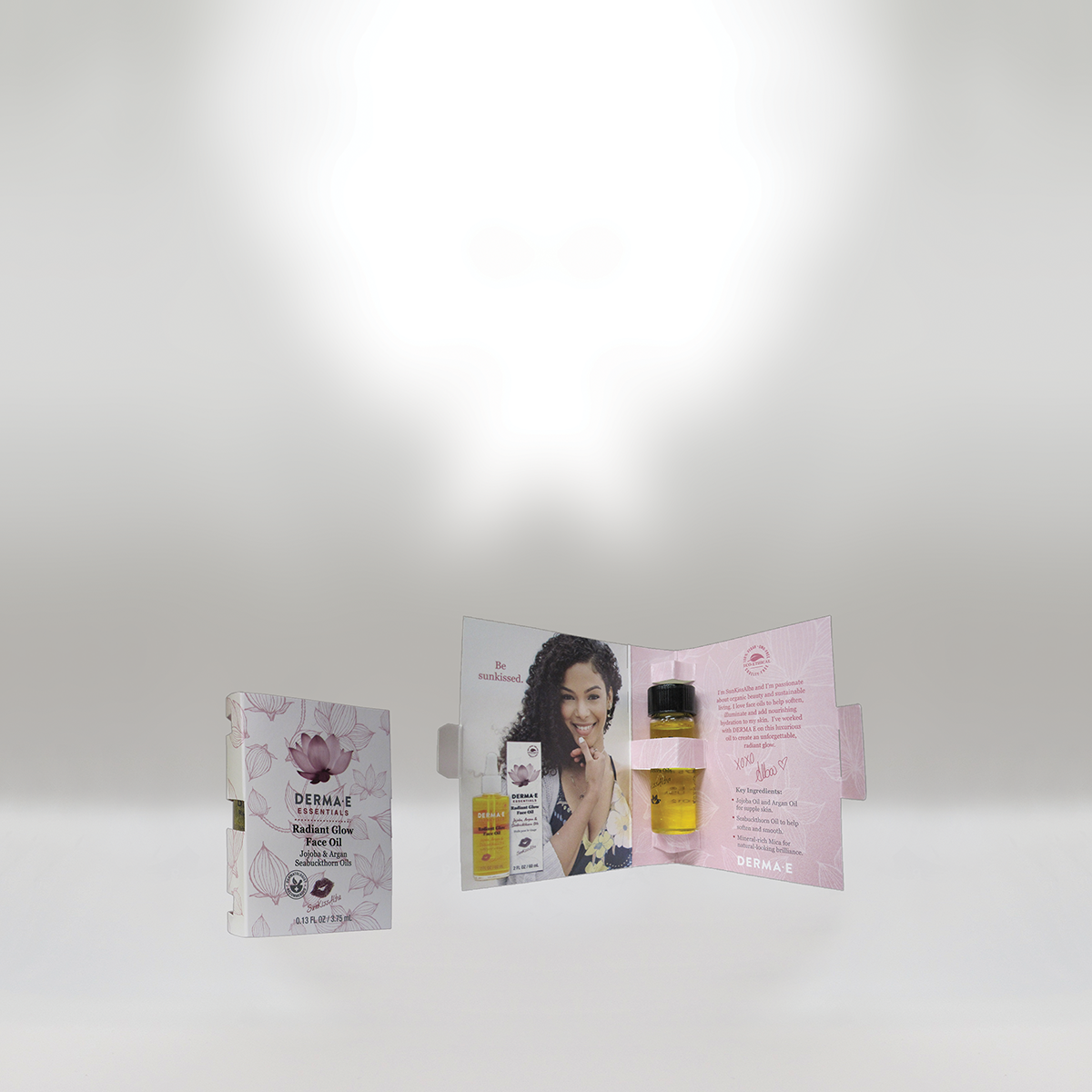 Open promotional display for DERMA E Radiant Glow Face Oil with a smiling woman and product information.