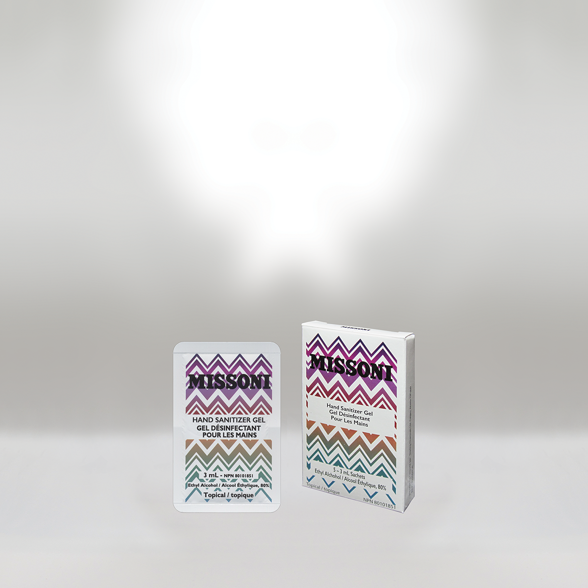 Small box and sachet of Missoni hand sanitizer gel with zigzag patterned packaging in purple, orange, green, and beige colors, and labeled as 80% ethyl alcohol.