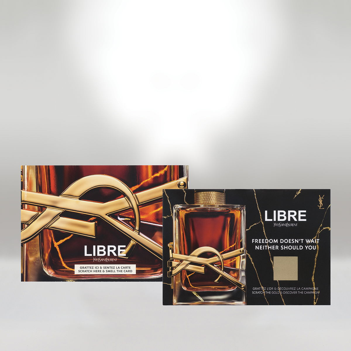 Yves Saint Laurent Libre perfume bottle with black packaging featuring gold marble accents, and a card with the perfume’s name and tagline being held behind the bottle.