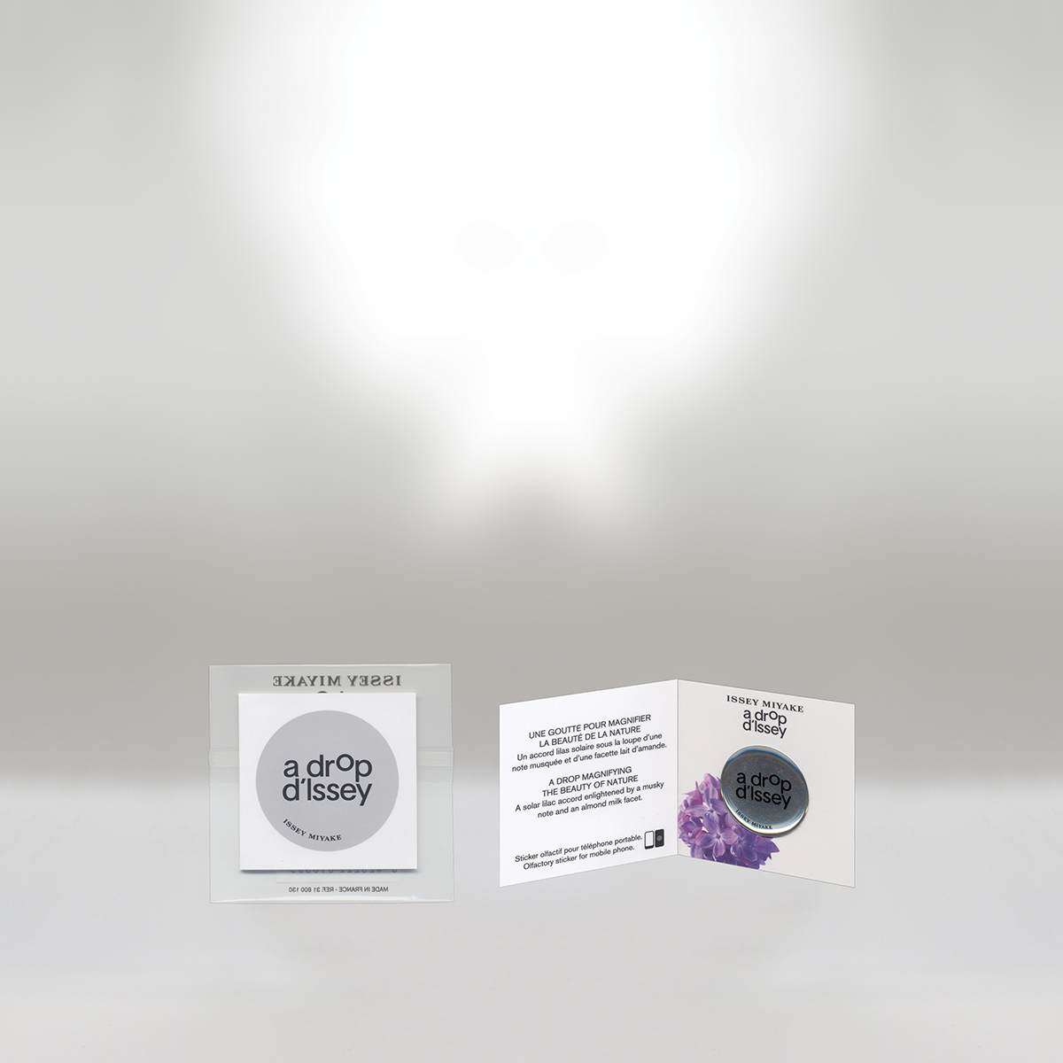 Open packaging for Issey Miyake a drop d'Issey perfume with a promotional brochure featuring purple flowers and a circular mirror.