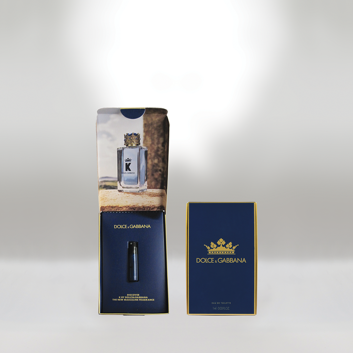 Une boîte de parfum Dolce & Gabbana avec un flacon de parfum à l'intérieur et l'emballage extérieur de la boîte sur un fond uni.