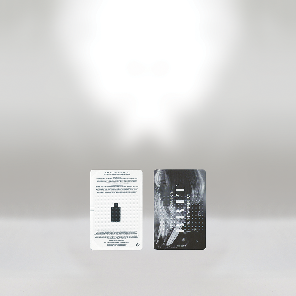 Two cards, one white with black text and a bottle icon, and one black with a woman's profile and white text, lie on a light-colored surface.