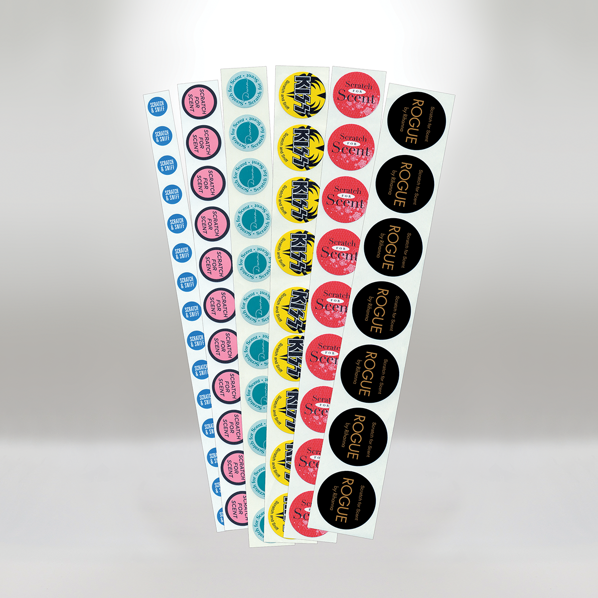 Multiple sheets of scratch-and-sniff scent stickers in blue, pink, yellow, and black colors with various brand labels.