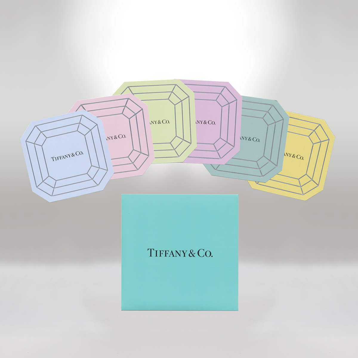 Colorful Tiffany & Co. jewelry boxes in pink, yellow, green, blue, and purple arranged in a semi-circle with a large blue box in the front.
