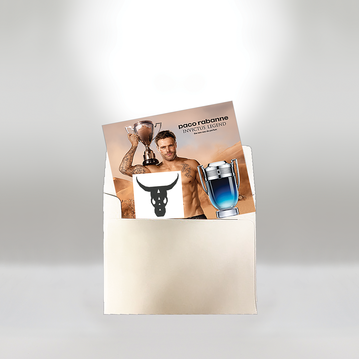 Affiche promotionnelle pour Paco Rabanne Invictus Legend représentant un homme torse nu avec des tatouages tenant un trophée, sur fond de désert, avec de grandes images du flacon du parfum et un logo de taureau sur l'affiche.