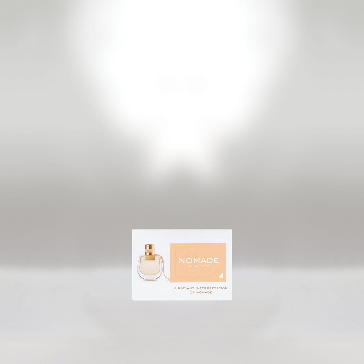 Perfume bottle and box labeled 'Nomade Eau de Toilette' on a white background.