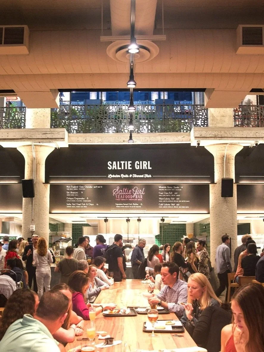 Image of a food hall with a menu and people.