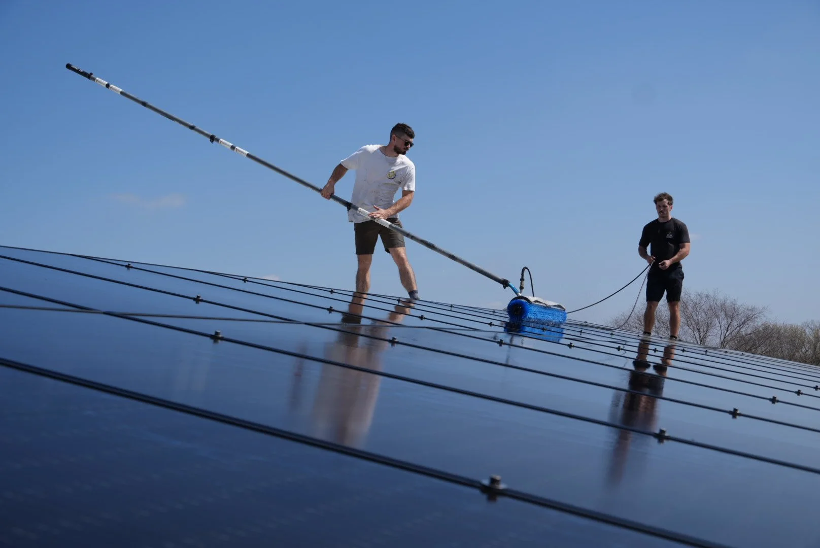 Solar Scapes crew on a roof cleaning solar panels.