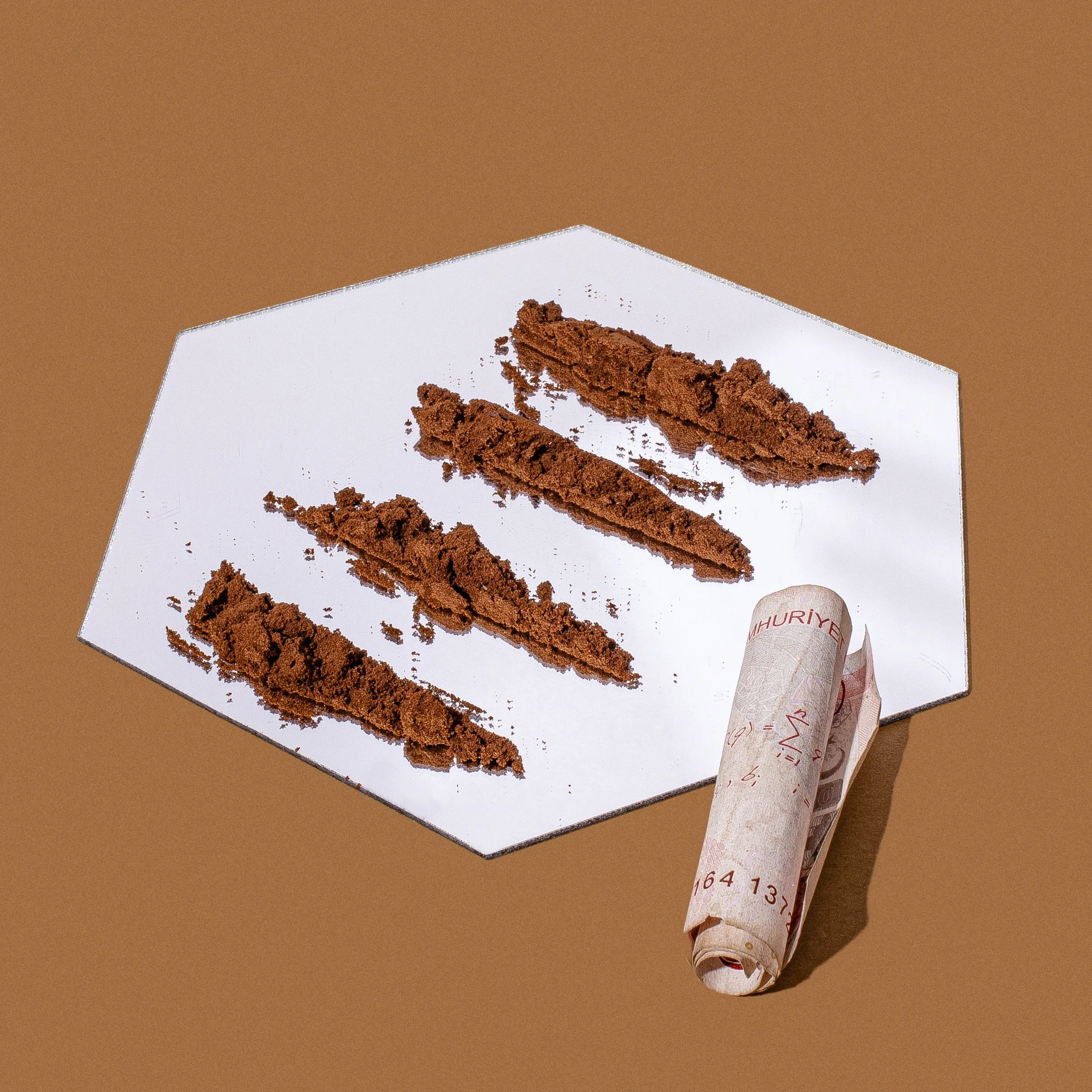 Finely ground Turkish coffee powder lined on a mirror next to a rolled Turkish lira bill, styled as a humorous product photo by Dr. Honeybrew NYC